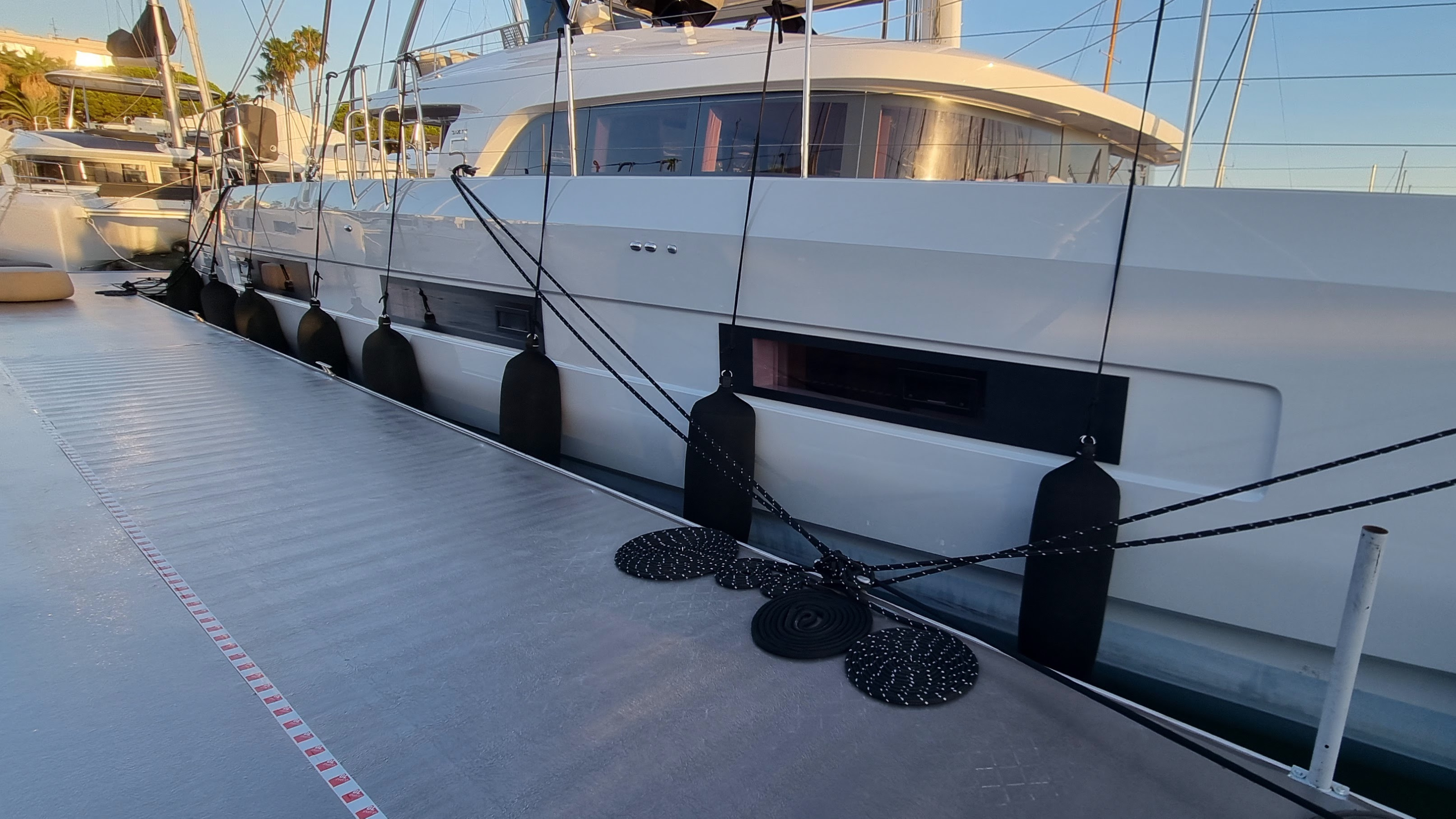Catamaran docked in a marina and protected from the dock with fendertex boat fenders.