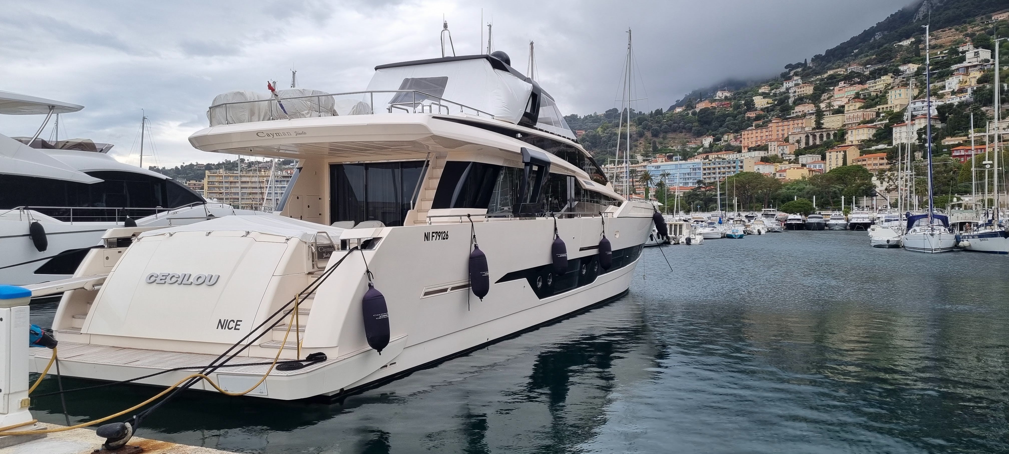 Yacht docked in a marina with a scenic background and protected from bumping against other boats with fendertex inflatable textile fenders. 